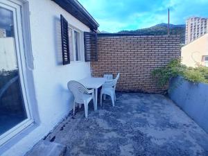 a table and chairs on a patio with a brick wall at Igalo Vuke in Igalo