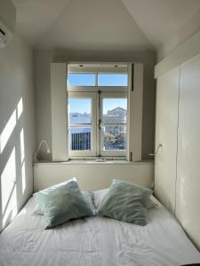 1 cama con 2 almohadas en una habitación con ventana en Porto Cinema Apartments, en Oporto