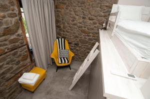a small room with a bed and a yellow chair at Nephelis Heritage House in Moúdhros