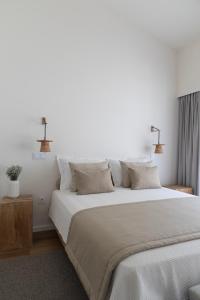 a bedroom with a large bed with white sheets and pillows at Casa da Milheira - Agroturismo in Oliveira de Azemeis