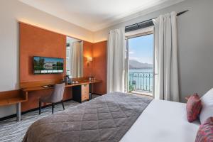 a hotel room with a bed and a desk and a window at Impérial Palace in Annecy