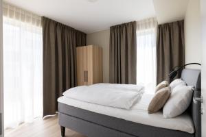 a bedroom with a large bed with white sheets and pillows at Stay North Paradis in Stavanger