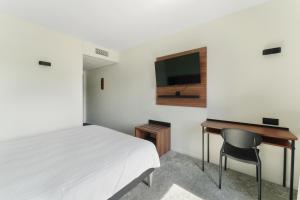 a bedroom with a bed and a desk and a television at Hôtel Akena Pierrelaye in Pierrelaye