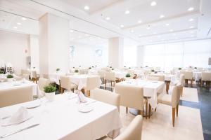 a dining room with white tables and chairs at Aparthotel Albufera in Alfafar