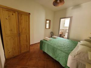 a bedroom with a green bed and a wooden cabinet at Mamalù Deluxe in Lampedusa