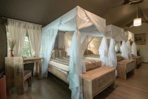 a bedroom with a canopy bed with a bench and a table at Mara Maisha Camp in Talek +82 photos