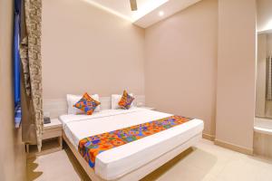 a white bedroom with a bed with colorful sheets at FabHotel Kitchen Q Inn - Belaghata in Kolkata