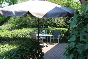 a table and chairs under an umbrella in a garden at Ferienhaus am Belmermoor 167 in Brunsbüttel
