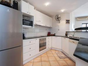a kitchen with white cabinets and stainless steel appliances at Darwin Esplanade Walk to Waterfront Wines and Waves in Darwin