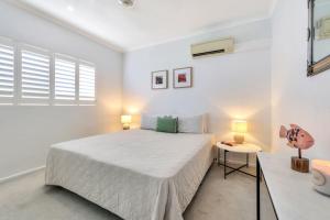 ein weißes Schlafzimmer mit einem großen Bett und einem Tisch in der Unterkunft 2 Bedroom Top Floor Parap Delight New to Market in Parap + 15 Fotos