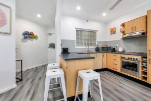 eine Küche mit Holzschränken und weißen Hockern in der Unterkunft 2 Bedroom Top Floor Parap Delight New to Market in Parap