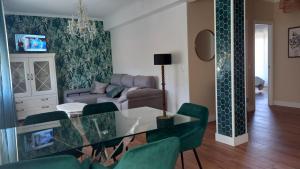 a living room with a glass table and green chairs at apartamento con jardín in A Guarda