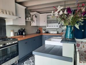 a kitchen with blue cabinets and a vase of flowers at Gîte La Boutardière in Saint-Aubin-le-Cloud