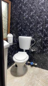a bathroom with a toilet and a black tiled wall at Casa Haidu in 2 Mai