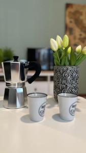 three cups and a coffee pot and flowers on a table at Appartamento a Luino Cavallotti25 in Luino +5 photos
