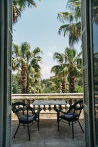 a patio with a table and chairs and palm trees at Bed and Breakfast in an exceptional villa in Le Pradet