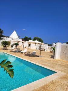 ein Swimmingpool mit Stühlen und ein Haus in der Unterkunft Trullo il Gelso with Private Salt Water Infinity Pool and Jacuzzi inside in San Michele Salentino