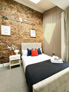 a bedroom with a large bed and a brick wall at Farringdon Rooms in London +50 photos