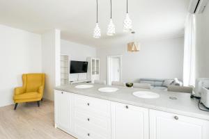 a white bathroom with two sinks and a yellow chair at Business & Family Apartment Letna in Košice