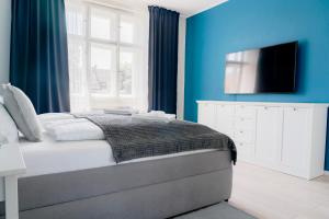 a bedroom with blue walls and a bed with a television at Business & Family Apartment Letna in Košice