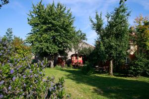 a house with trees and flowers in the yard at La Chouette Roulotte in Fresnay