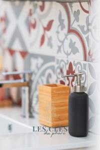 a black soap dispenser sitting on a bathroom counter at La Bargnia : Maison Touquettoise in Le Touquet-Paris-Plage