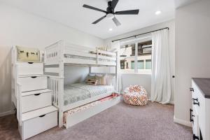 een slaapkamer met witte stapelbedden en een plafondventilator bij Paradise Cove condo in Atkinville