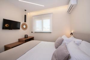 Kalopsia Luxury Apartment Near Chania في مدينة خانيا: غرفة نوم بها سرير وتلفزيون على الحائط