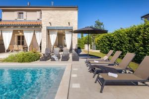 a pool with lounge chairs and an umbrella next to a house at Villa Calma in Šivati
