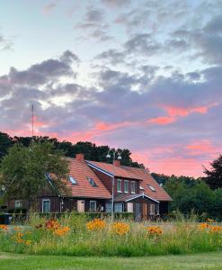 a house with a field of flowers in front of it at Neringarent Apartamentai in Juodkrantė