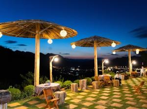 a patio with tables and umbrellas at night at Green farm home & coffee in Làng Môn