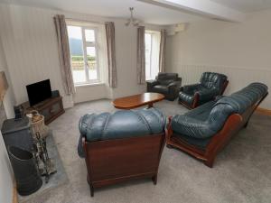 a living room with leather furniture and a television at The Old Post Office in Haverfordwest