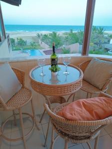 a table with a bottle of wine and two glasses at Flat Malua - Apartamento Pé Na Areia Com Vista Mar Taíba-CE in Taíba