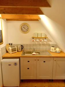 a kitchen with a sink and a clock on the wall at Rustic Retreat Guest Lodge in Littleport