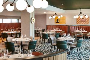 a dining room with tables and chairs and chandeliers at Manchester Marriott Hotel Piccadilly in Manchester