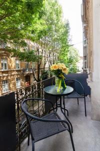 a table and chairs on a balcony with a vase of flowers at Royal mini apart-hotel on Kovzhyna in Lviv