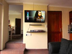 einen Flachbild-TV an der Wand im Wohnzimmer in der Unterkunft Suburban oasis in quiet neighborhood in Johannesburg