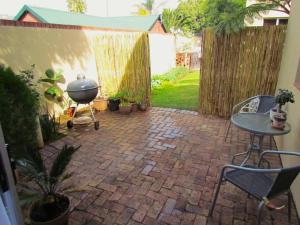 eine Terrasse mit einem Grill, einem Tisch und Stühlen in der Unterkunft Suburban oasis in quiet neighborhood in Johannesburg