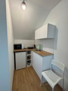 a small kitchen with white cabinets and a white chair at Przystanek Zator in Zator