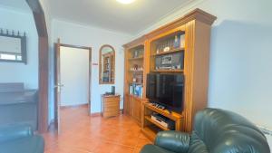 a living room with a tv and a leather couch at Villa for Short Term Medium Long Stay in Trofa