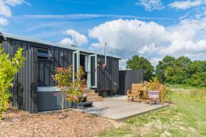 a black tiny house with a wooden deck at Ernest by Bloom Stays in Tenterden
