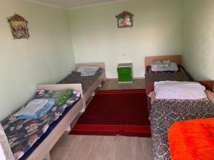 a room with three beds and a red carpet at Гостевой дом in Cholpon-Ata
