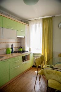 Una cocina con gabinetes verdes y una mesa y una ventana. en Family apartment on Shevchenko street, en Vínnytsia
