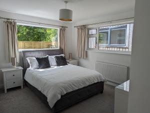 a bedroom with a large bed and two windows at Peaceful Glastonbury Bungalow - Ideally Located in Glastonbury
