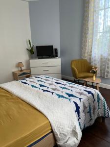 ein Schlafzimmer mit einem Bett, einem Fernseher und einem Stuhl in der Unterkunft 3Chambre calme première étage in Montgeron