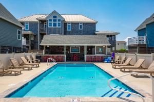 une piscine avec des chaises et une maison dans l'établissement NH387F Cape Hatteras Cottage, à Nags Head