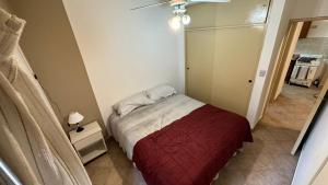 a small bedroom with a bed with a red blanket at Departamento 1 dormitorio - Tucutemps in San Miguel de Tucumán