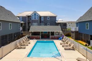 une piscine avec des chaises longues et une maison dans l'établissement NH387E Currituck Cottage, à Nags Head