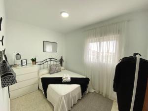 ein weißes Schlafzimmer mit einem Bett und einem Fenster in der Unterkunft Apartamento Malandar in Sanlúcar de Barrameda