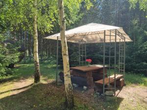 a tent with a wooden table in a forest at Privaatne puhkemajake koos saunamajaga in Metsakivi